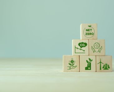 Net zero and carbon neutral concept. Net zero greenhouse gas emissions target. Climate neutral long term strategy. The wooden cubes with green net zero icon and save world icon on grey background.