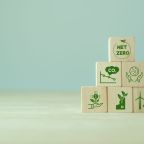 Net zero and carbon neutral concept. Net zero greenhouse gas emissions target. Climate neutral long term strategy. The wooden cubes with green net zero icon and save world icon on grey background.