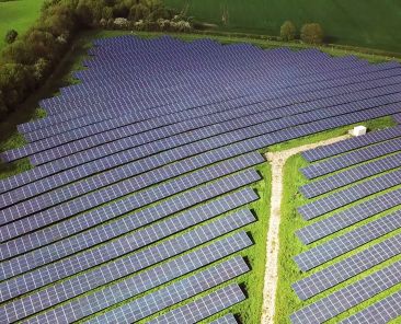 Solar panels farm between agriculture fields in aerial view.